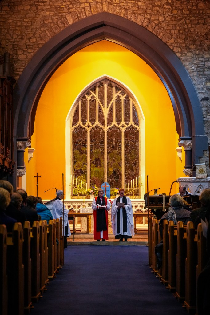 Ornate gothic window of St. Patrick's Cathedral, Trim, illuminated with warm golden light, showing the architectural details and stained glass